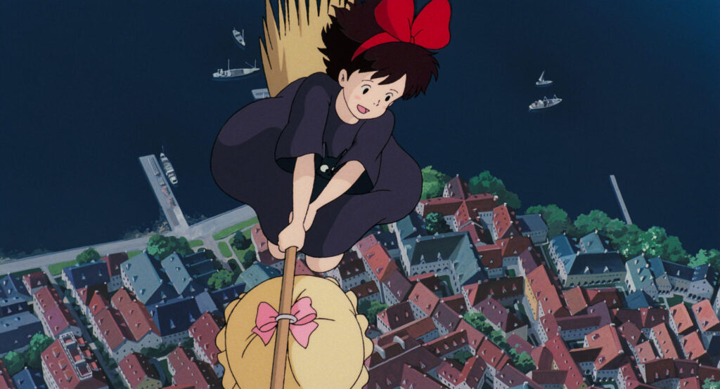 alt="Kiki flying over the city with her broom from Kiki’s Delivery Service(魔女の宅急便のキキがホウキで街の上を飛ぶ)"