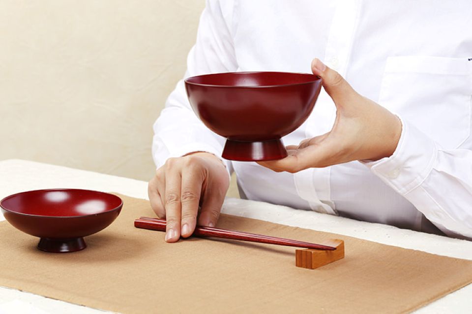 A person holding a Japanese rice bowl while eating