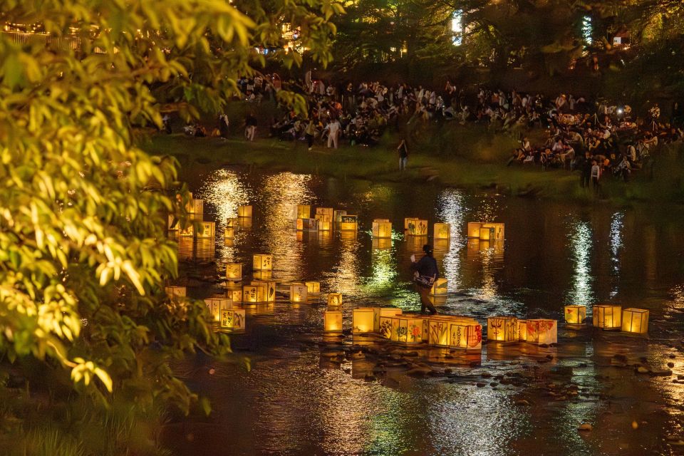 Lanterns floating down a river at night during Obon in Japan