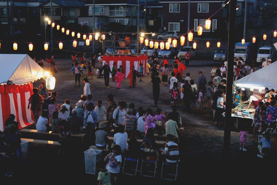 Crowds enjoying a Japanese summer festival at night with lanterns and food stalls
