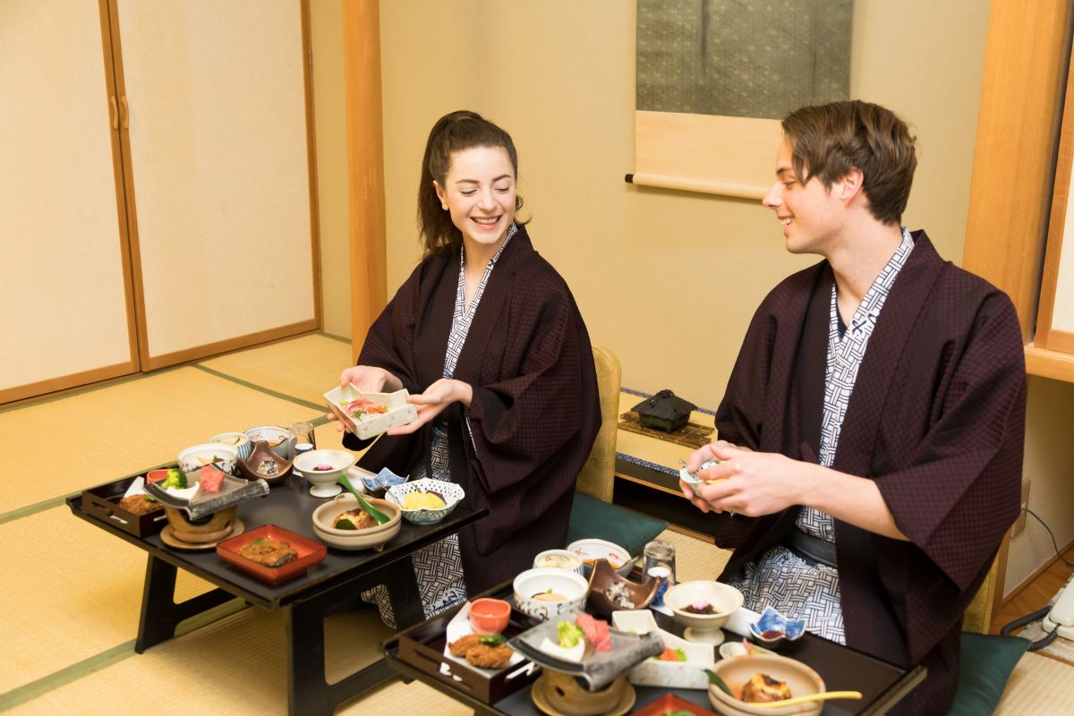 Two travelers enjoying a traditional Japanese meal in a tatami room